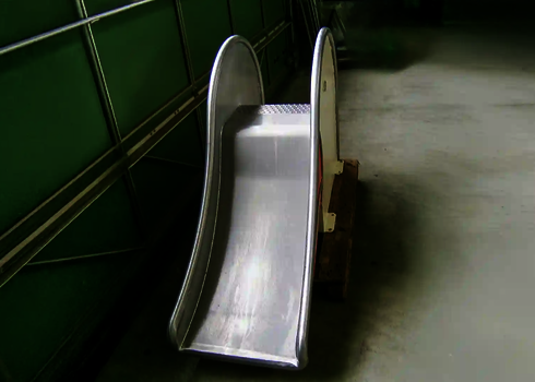  Edelstahlrutsche mit leichtem Gefälle, in einer Halle auf Holzpalette platziert.