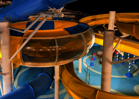 Gelb-blaue Body Bowl bei Nacht mit beleuchteter Spiralrutsche und Röhrenrutsche.