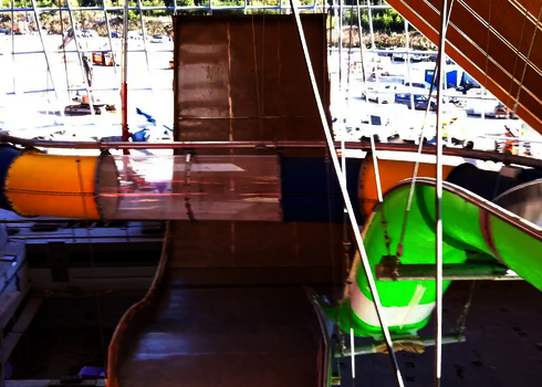 Blick auf eine Boomerang Rutsche, im Vordergrund eine gelb-blaue Röhrenrutsche.