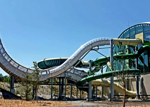 Außenbereich eines Schwimmbades mit Blick auf verschiedene edel aussehende Wasserrutschen.
