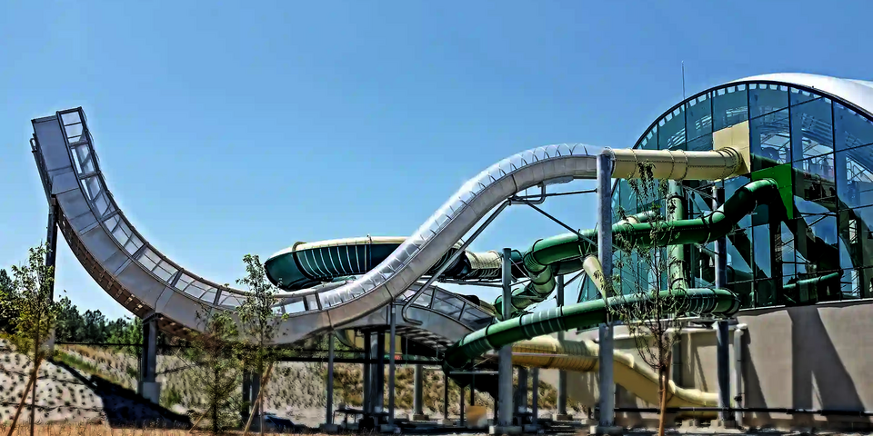 Außenbereich eines Schwimmbades mit Blick auf verschiedene edel aussehende Wasserrutschen.
