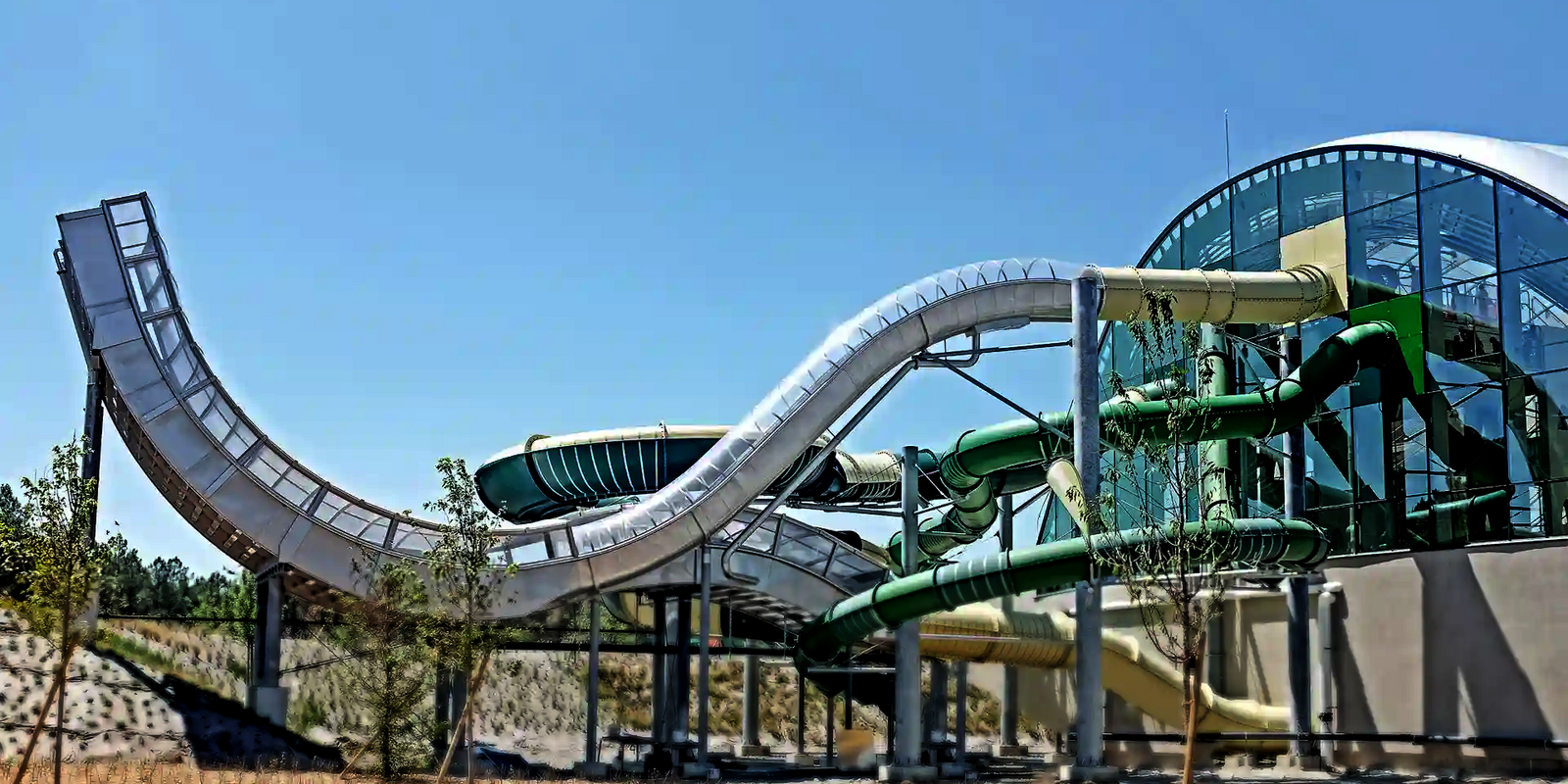 Außenbereich eines Schwimmbades mit Blick auf verschiedene edel aussehende Wasserrutschen.