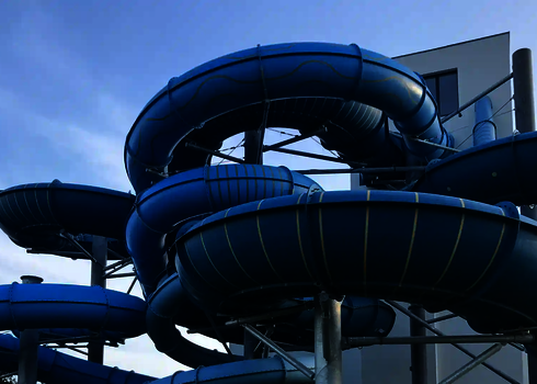 Mehrspurige blaue Family Twister Reifenrutsche mit engen Kurven an einem Gebäudekomplex.