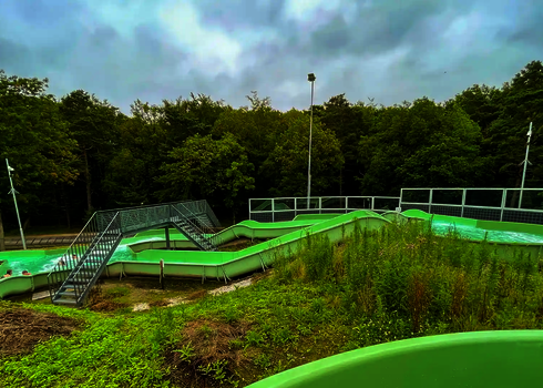 Grüner Wildwasserfluss führt durch parkähnliche Umgebung.