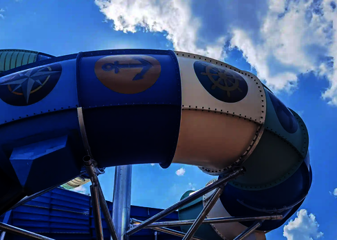 Rutschenkurve mit sichtbaren Tageslichtmotiven wie Kompass, Anker und Steuerrad vor blauem Himmel.