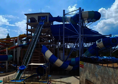 Raft conveyor with blue slide raft between colorful water slides and large spiral slide.