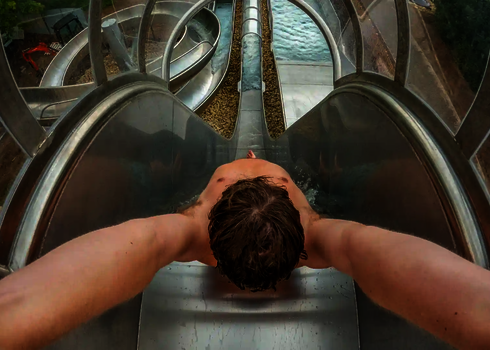 Start einer Edelstahl-Freifallrutsche mit Blick auf Auslauf und kurvige Nachbarrutschen.