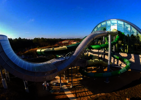 Die Reifenrutsche Boomerang verläuft kurvig von einem gläsernen Gebäude ins Freie.