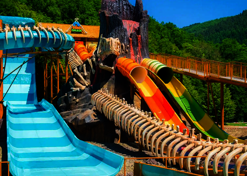 Freizeitpark mit Dinosaurier-Theme  mit mehreren bunten Wasserrutschen.