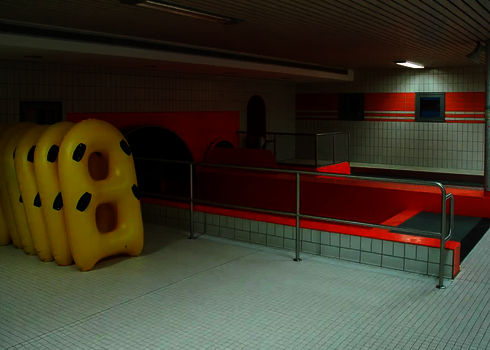 Yellow double tyres stand next to two red slide exits in an indoor facility.