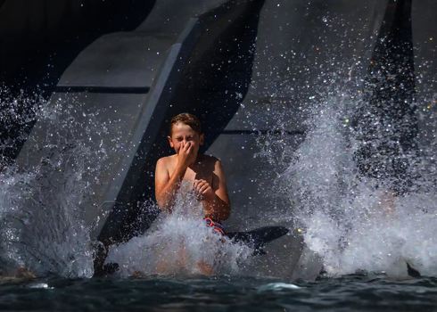 Ein Mädchen rutscht lachend auf der mittleren Bahn der Trio-Slide ins Wasser.