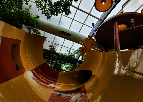 Kinder Cone Wasserrutsche in tropischer Umgebung unter Glasdach.