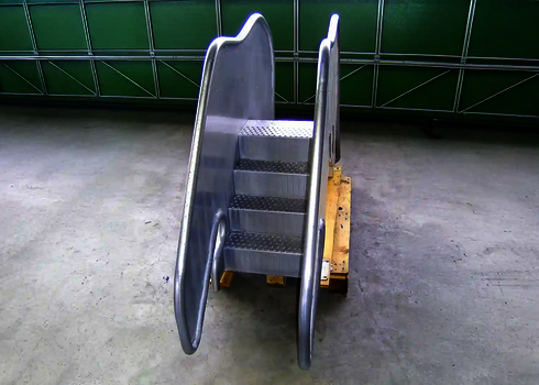  Kompakte Edelstahlrutsche mit vier Stufen, steht auf Palette in einer Produktionshalle.