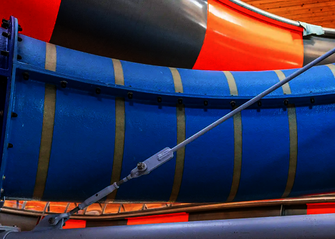 Blau gestreifte Wasserrutsche in einer Indoor-Anlage, befestigt mit Stahlseilen.