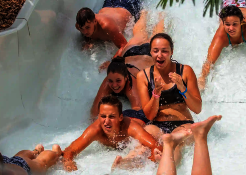 Eine Gruppe Jugendlicher rutscht gemeinsam durch den Wildwasserfluss.