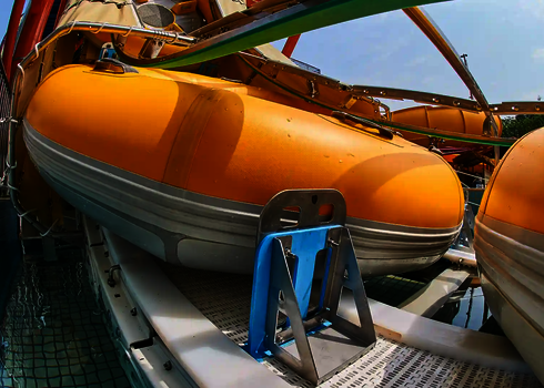 A yellow slide raft sits on a transport device of the raft conveyor in the water.