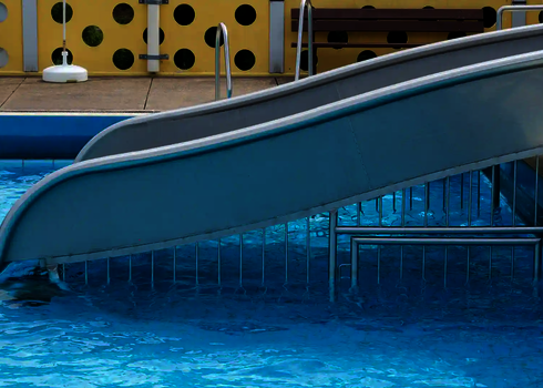 Breitwellenrutsche mit einem Unterschwimmschutzgitter in einem Schimmbecken.