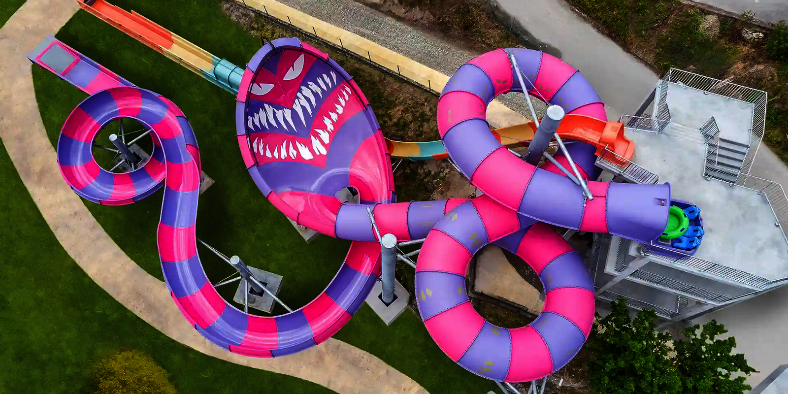 Luftaufnahme einer lila-pinken Wasserrutsche mit Monster-Gesicht als Thematisierung