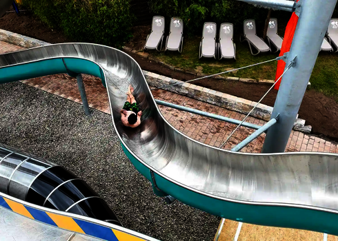 Person rutscht eine lackierte WR800 Edelstahlrutsche hinunter.