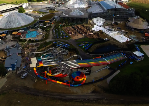 Luftaufnahme eines Wasserparks mit Edelstahlrutschen und bunten Rutschbahnen.