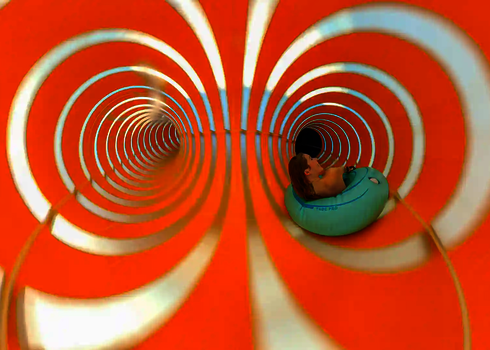 Zwei sichtbare Tunnelführungen einer orange weiß gestreiften Wasserrutsche.