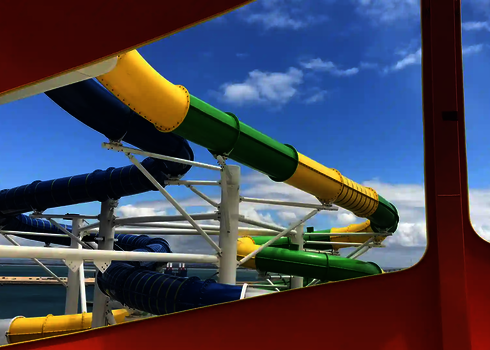 Rutschen in Blau, Grün und Gelb mit glatter Oberfläche, gerahmt durch orangen Sichtschutz.