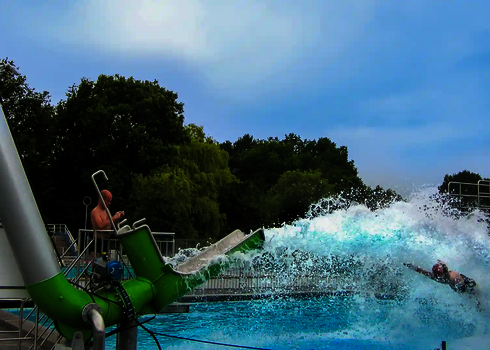 Großer Wasserschwall kommt aus einem grünen Cannonball, in einem Wasserpark.