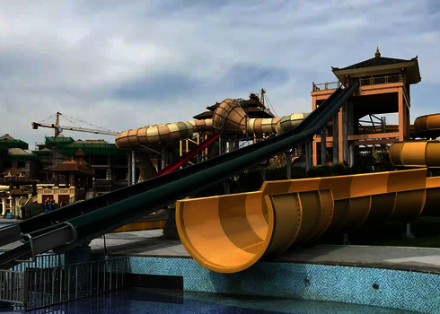 Raft conveyor leads upwards between tube slides in an Asian-style water park.