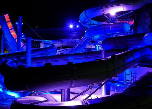 Komplexes Rutschensystem mit LED-Beleuchtung in Blau und Violett bei Nacht.