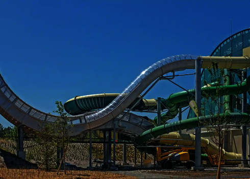 Seitenansicht der Boomerang-Reifenrutsche mit hoher Rampe neben mehreren Röhrenrutschen.