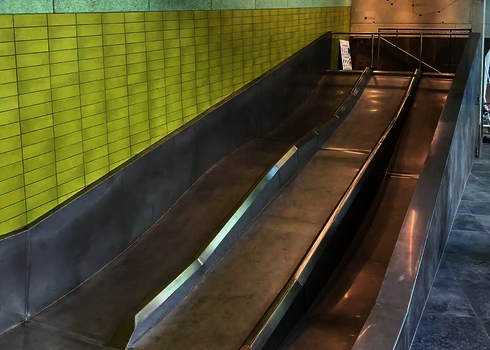 Leere Trio-Slide mit drei Edelstahlbahnen und seitlicher Fliesenwand in Gelb.