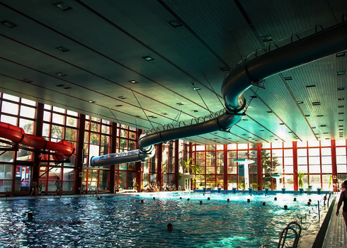 Edelstahlrutsche WR1040 verläuft über ein großes Hallenbad mit vielen Badegästen.