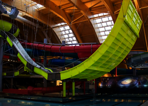 Rückansicht der Boomerang-Rutsche mit gelber Steilkurve und Seilabhängung.