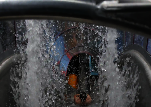 Frontansicht auf eine startende Person mit kräftigem Wasserzufluss in die Freifallrutsche.
