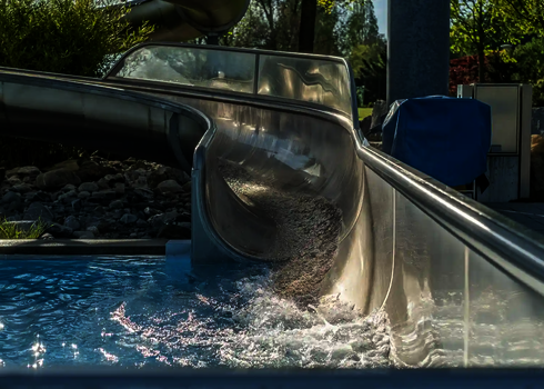 Nahaufnahme der Auslaufzone einer Edelstahlrutsche mit fließendem Wasser.