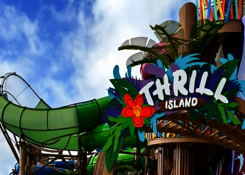 Eingangsbereich „Thrill Island“ mit grüner Lotus Reifenrutsche im Hintergrund.