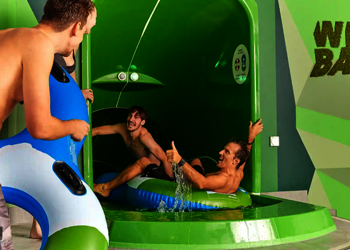 Drei Männer im Startbereich einer Wasserrutsche mit grüner Sensorampel.