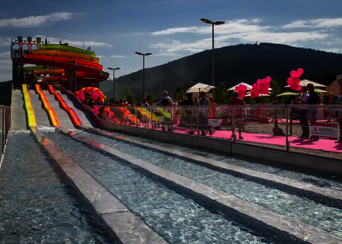 Besucher beobachten die bunte Wasserrutsche Matracer mit mehreren parallelen Rutschbahnen.