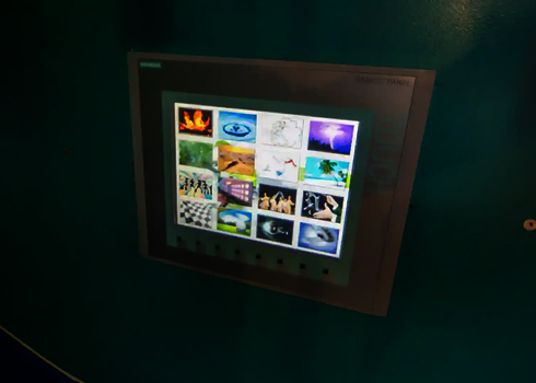 Touchscreen mit Auswahl bunter Themenwelten für Rutschenstart an türkisfarbener Wand.