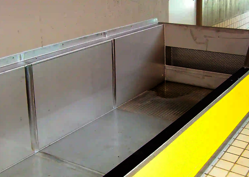 A stainless steel exit area with yellow side panels in an indoor swimming pool.