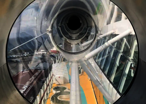 Blick durch eine transparente Röhre mit Aussicht auf Schiffsdeck und umliegendes Gelände.