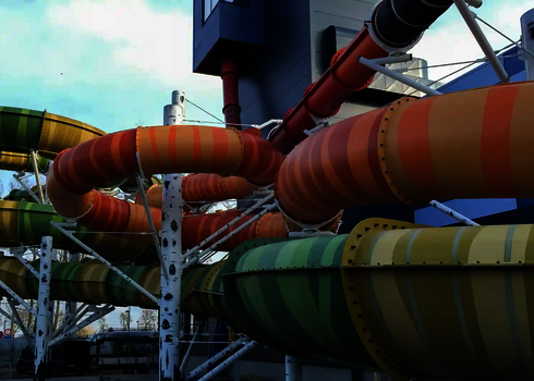 Bunte GFK Wasserrutschen und eine U-Drop Wasserrutsche im Hintergrund.