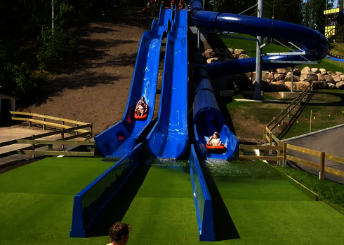 Landebereich von drei blauen Wasserrutschen in einem Freizeitpark.