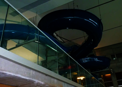 Blaue Wasserrutsche des Typs RR1400  hängt an der Decke, im Vordergrund ein Glasgeländer.