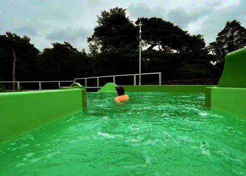Ein Mann mit Kamera treibt im offenen Auslaufbereich des Wildwasserflusses.