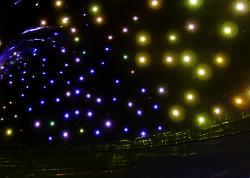 Bunte LED-Lichter leuchten in einer dunklen Röhrenrutsche in Blau, Gelb und Weiß.