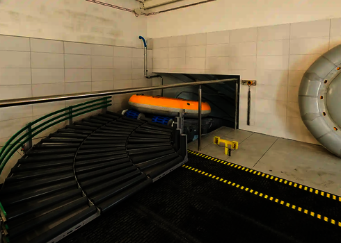 A yellow slide raft lies on a curved roller system at the entrance to the raft conveyor.
