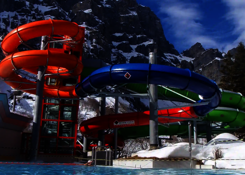 Eine RR1200 Wasserrutsche in grün, orange und blau vor einem schneebedeckten Gebirge.