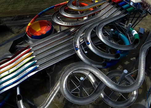 Blick von oben auf einen großen Rutschenkomplex aus Edelstahl und GFK.