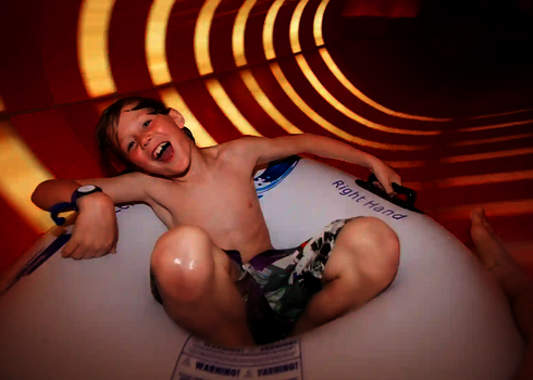 Eine Familien-Wasserrutsche von innen mit Streifen und einem Kind auf einem Rutschreifen.